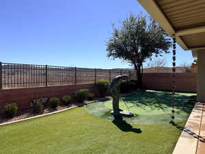 Fenced backyard with a patio area and an area to practice putting