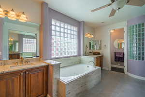 Bathroom featuring a ceiling fan, two vanities, tile patterned flooring, and a garden tub