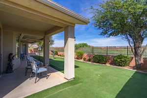 Fenced backyard with a patio and a putting green