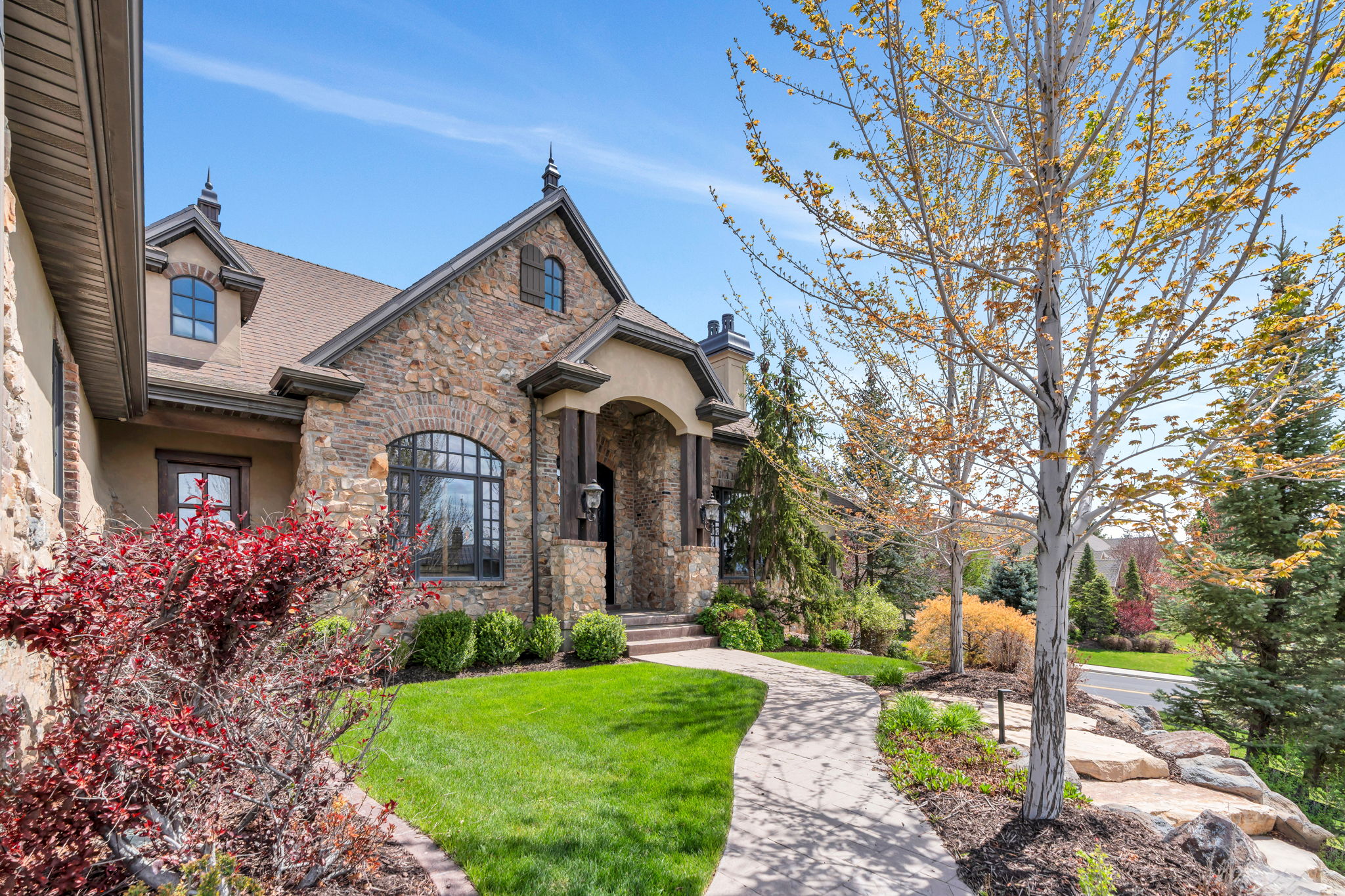 View of front of home featuring a front yard, a chimney, stucco siding, stone siding, and a shingled roof
