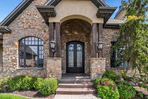 Property entrance with french doors, stone siding, and stucco siding