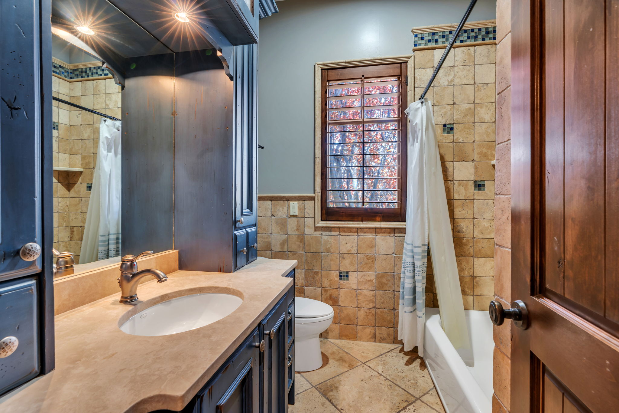 Full bath with vanity, shower / tub combo, tile walls, and wainscoting