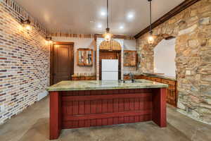 Kitchen featuring glass insert cabinets, freestanding refrigerator, dark stone countertops, pendant lighting, and a kitchen island with sink