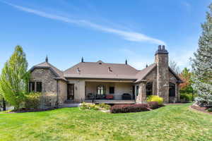 Back of house featuring stone siding, a chimney, stucco siding, a deck, and roof with shingles
