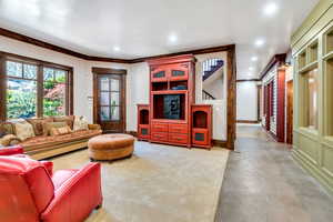 Living room with finished concrete flooring, recessed lighting, and crown molding