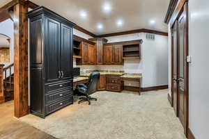 Office with ornamental molding, built in study area, recessed lighting, arched walkways, and light colored carpet
