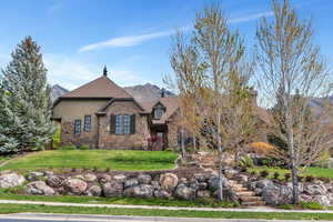 View of front of home with a mountain view, stone siding, a front lawn, and stucco siding