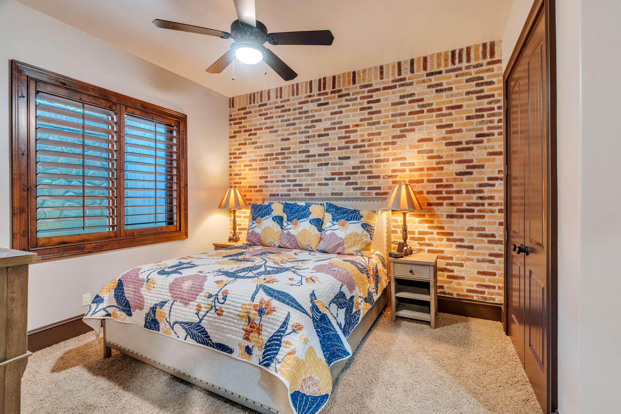 Bedroom featuring brick wall, a ceiling fan, and an accent wall
