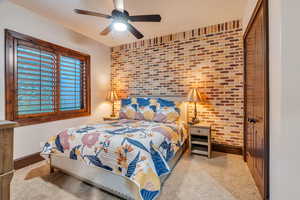 Bedroom featuring brick wall, a ceiling fan, and an accent wall