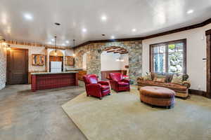 Living room with bar with sink, arched walkways, recessed lighting, and concrete floors