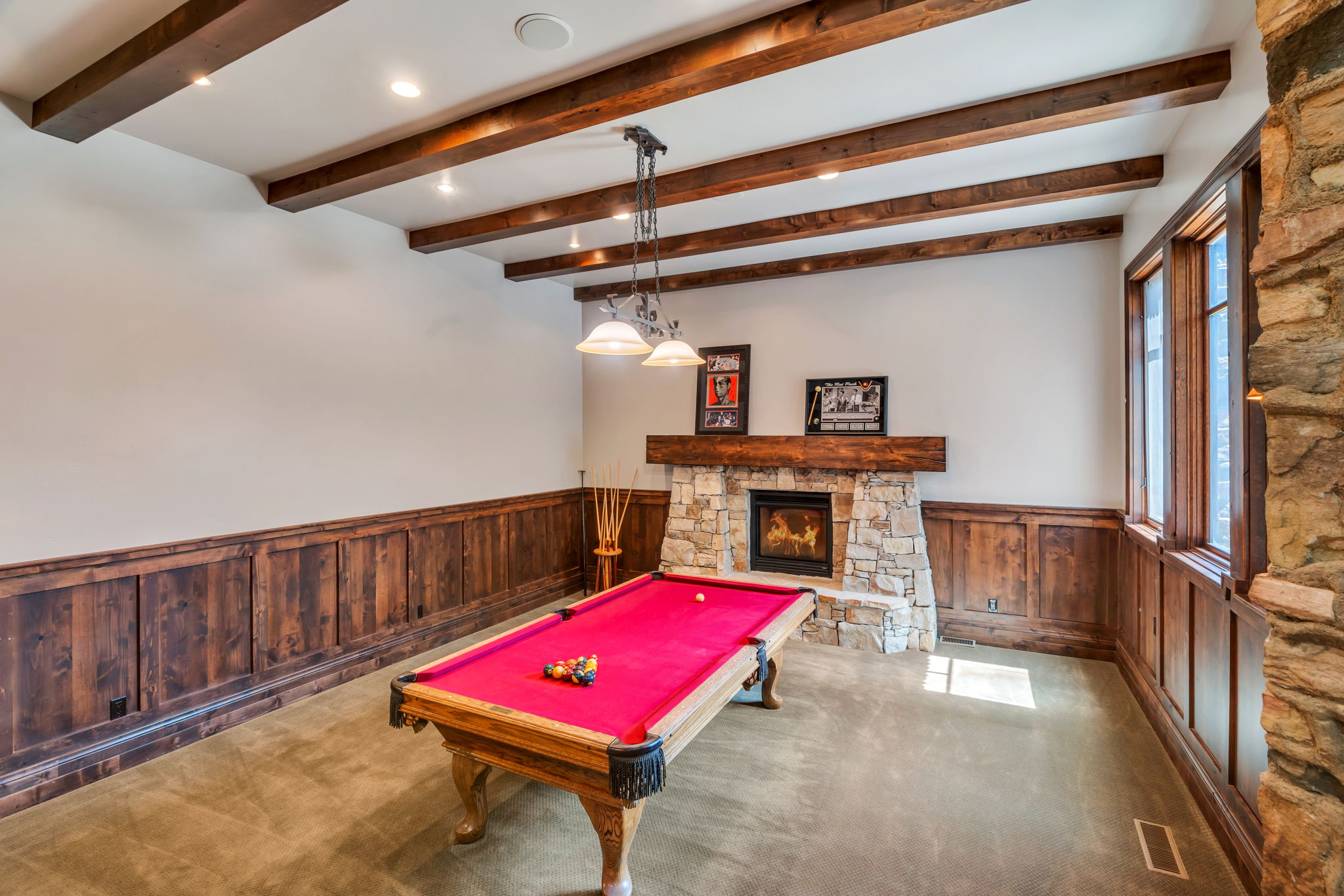 Playroom with a wainscoted wall, wooden walls, billiards table, carpet, and a stone fireplace