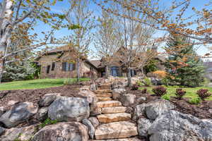 View of front of home featuring a front yard, a chimney, stone siding, and stucco siding