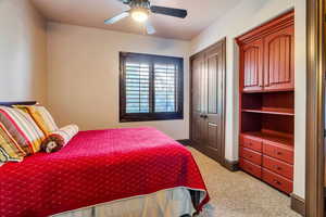 Bedroom with a closet, ceiling fan, and carpet flooring