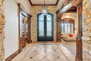 Entryway featuring french doors, arched walkways, crown molding, and inlaid floor details