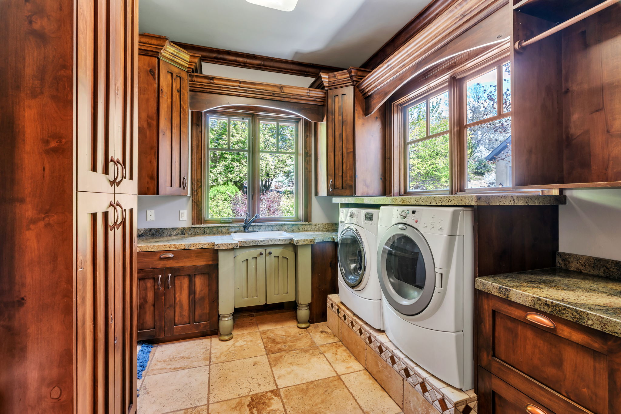 Laundry room featuring cabinet space, separate washer and dryer, and stone tile floors