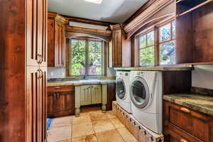 Laundry room featuring cabinet space, separate washer and dryer, and stone tile floors