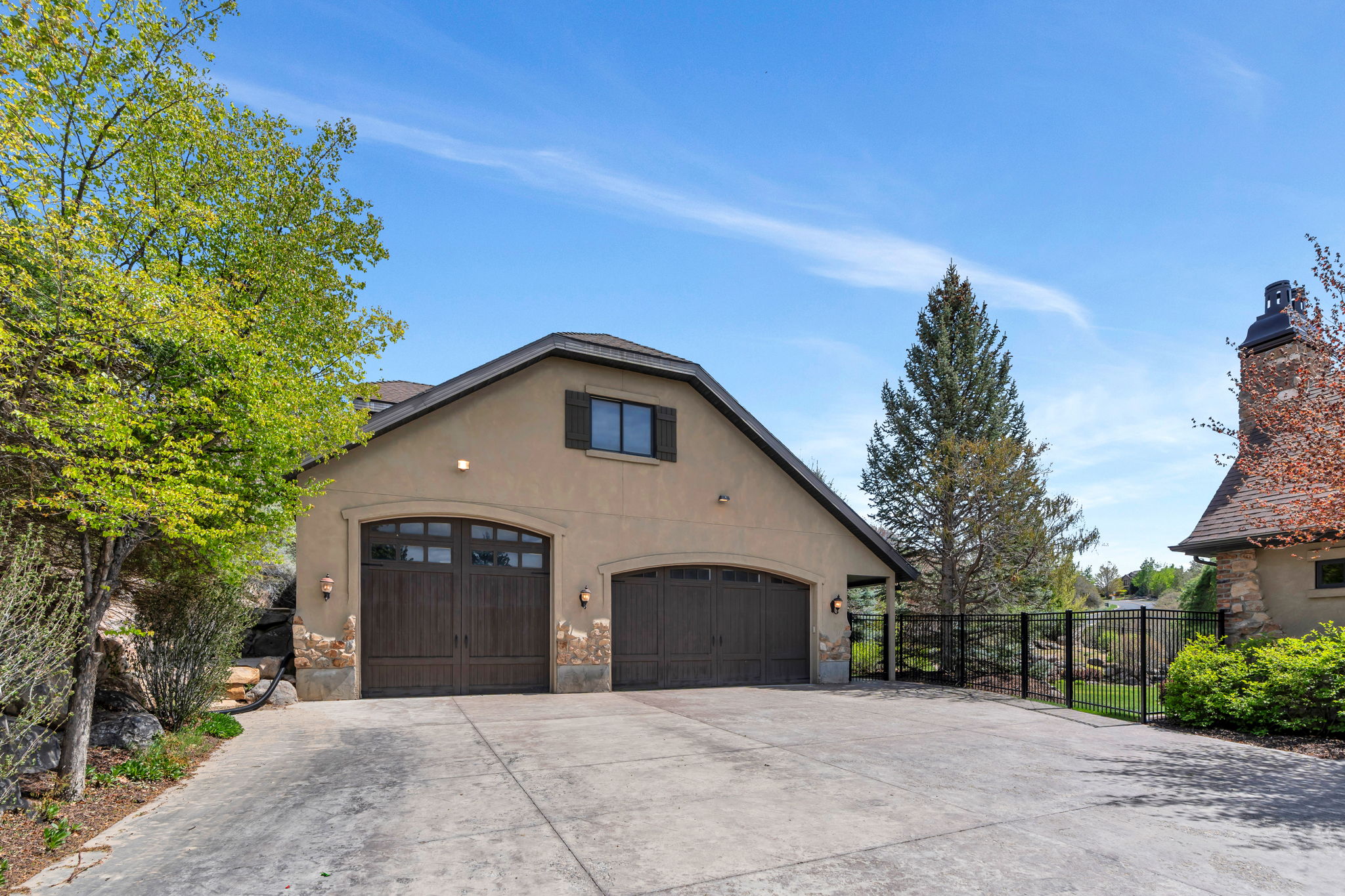 View of side of property with stucco siding, a garage, driveway, and a chimney