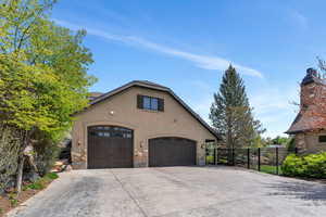 View of side of home featuring stucco siding, a garage, driveway, and a chimney