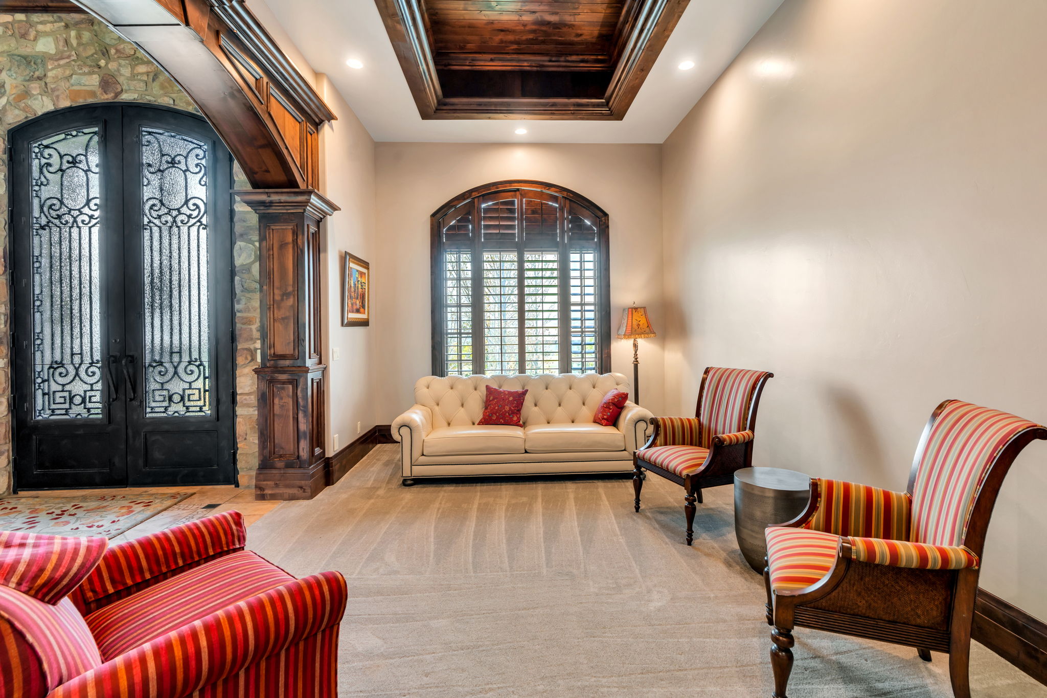 Living area featuring french doors, arched walkways, a raised ceiling, light carpet, and recessed lighting