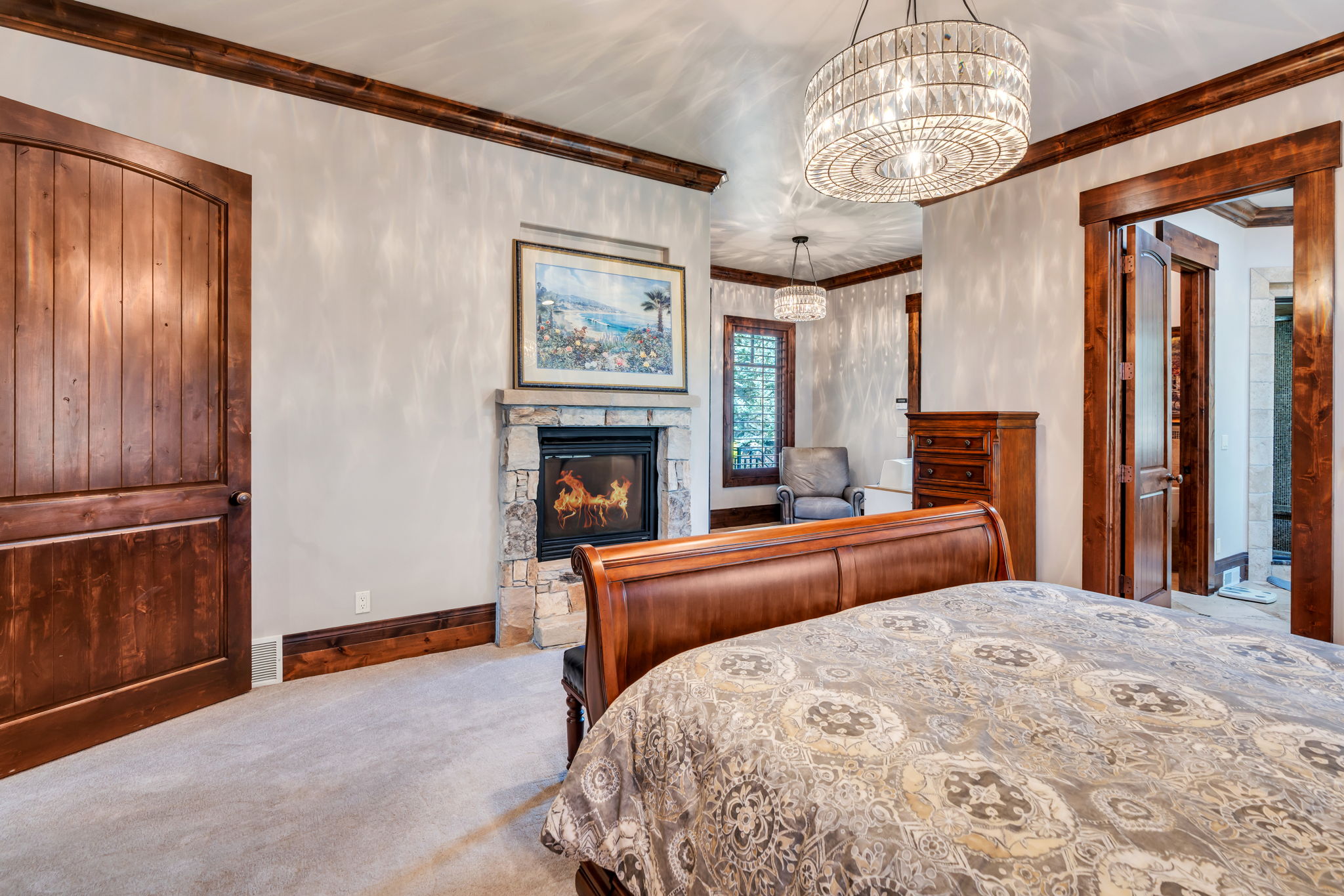 Carpeted bedroom featuring ornamental molding, a fireplace, and hanging lights