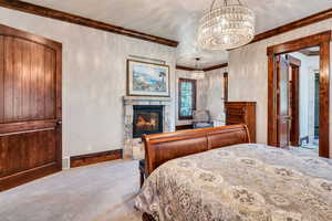 Carpeted bedroom featuring ornamental molding, a fireplace, and hanging lights