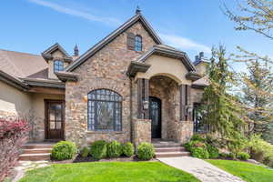 French country style house featuring stone siding, a front lawn, stucco siding, and a chimney