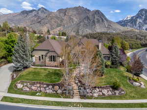 View of front facade featuring stone siding, a mountain view, a front lawn, stucco siding, and a chimney