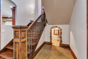 Stairway featuring arched walkways, concrete flooring, and a high ceiling