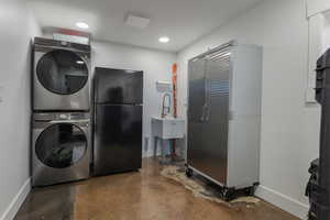 Laundry room featuring finished concrete flooring and stacked washer and clothes dryer