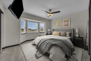 Bedroom with light colored carpet, ceiling fan, and a textured ceiling