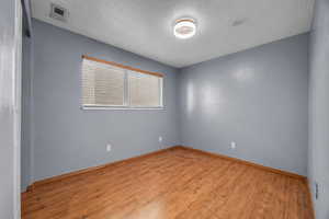Empty room featuring light wood-type flooring and a textured ceiling