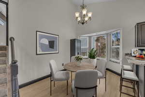 Dining room featuring light wood-type flooring, hanging lights, and a high ceiling