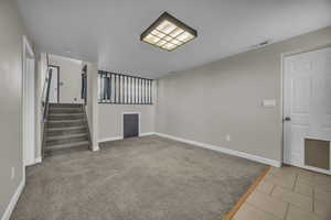 Unfurnished living room with stairway and light colored carpet