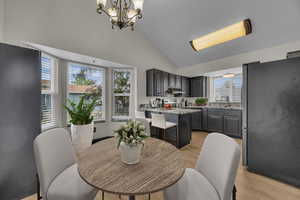 Dining area with a chandelier, light wood-type flooring, and vaulted ceiling