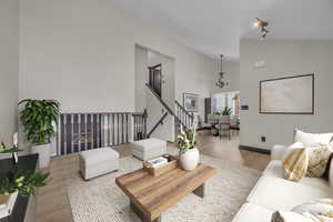 Living room with vaulted ceiling, light wood-style flooring, and suspended lighting
