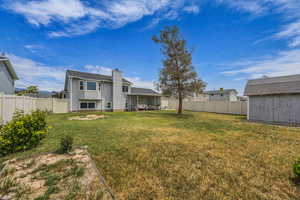 Rear view of property featuring a patio, a chimney, a fenced backyard, and a storage unit
