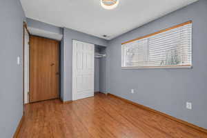 Unfurnished bedroom featuring a closet, light wood-style flooring, and a textured ceiling