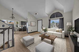Living area with light wood finished floors, vaulted ceiling, and hanging lights