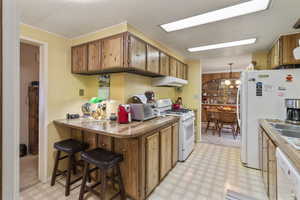 Kitchen with light flooring, white appliances, wooden counters, a breakfast nook, and wood finish cabinetry.