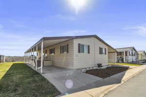 View of home's exterior featuring an attached carport, a porch, a lawn, and driveway