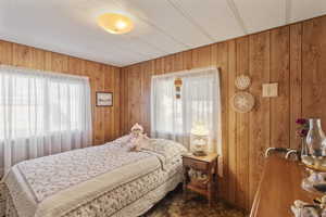 Carpeted bedroom featuring wooden walls and a textured ceiling.