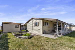 Back of property featuring a garden, a yard, a patio area, and a large Tuff Shed.