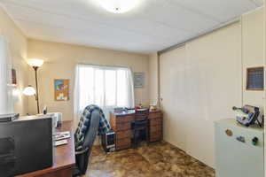 Home office with dark carpet and large closet on the right side of the image with sliding closet doors.