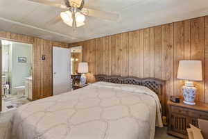 Bedroom featuring carpet, connected bathroom, ceiling fan, and wooden walls. Comfortably fits a king sized bedroom set.