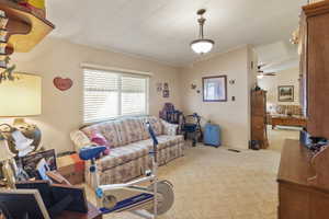 Living area with carpet floors, lofted ceiling, ceiling fan, and crown molding. Could be used as an office, flex space, or a more formal dining area.