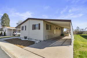 View of property exterior with a carport and stone landscaped front.