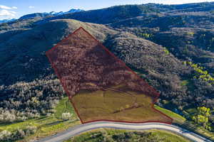 Aerial view of property and surrounding area with property boundaries highlighted and a mountainous background