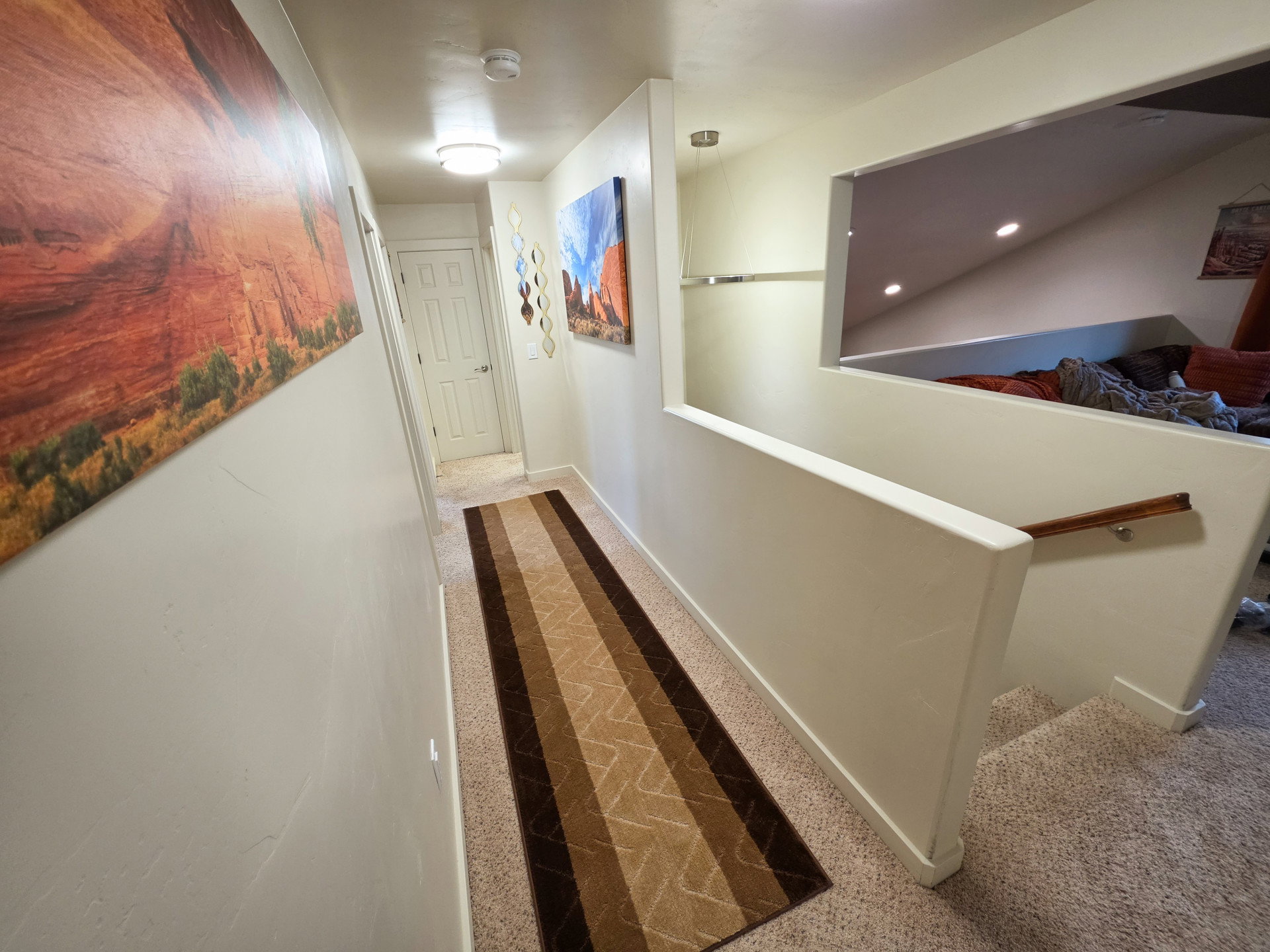 Hallway with light beige walls and a patterned runner over carpeted flooring
