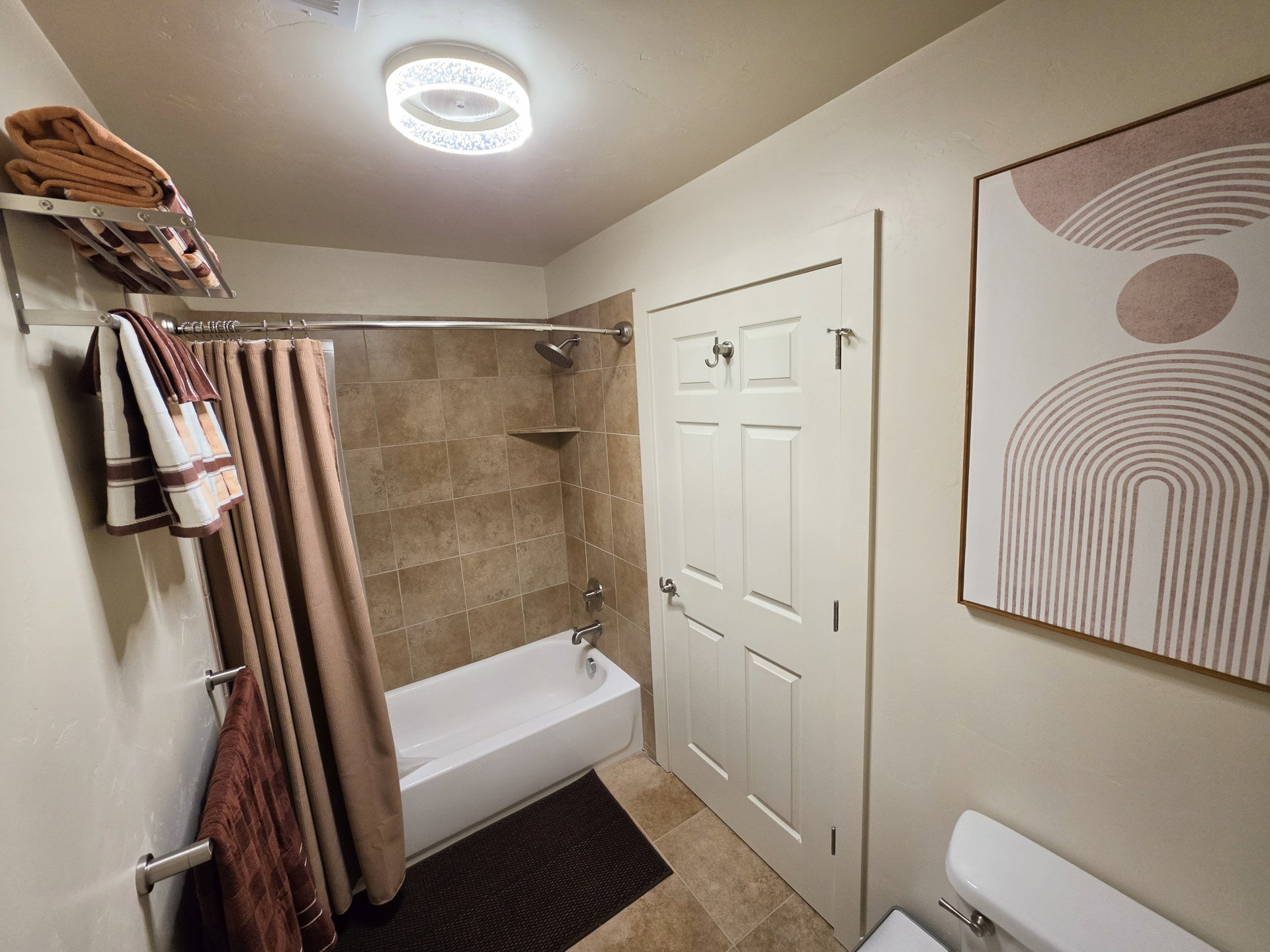 Bathroom featuring a white bathtub with a chrome showerhead, full-height tile surround, and a built-in shower niche
