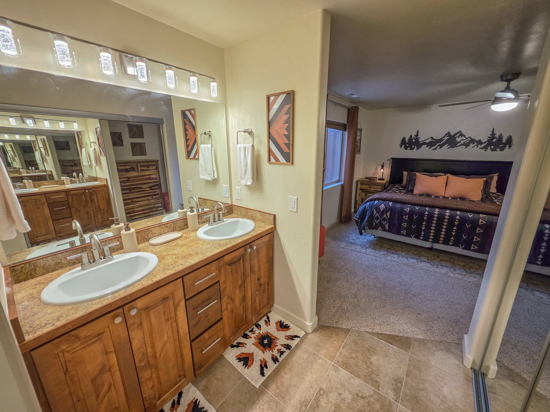 Dual vanity with undermount sinks, wood cabinetry, and a full-width mirror